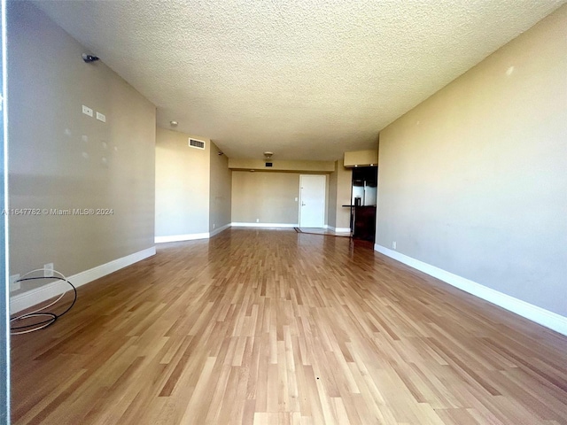 unfurnished living room with a textured ceiling and light hardwood / wood-style flooring