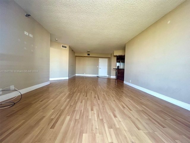 unfurnished living room with a textured ceiling and light hardwood / wood-style flooring