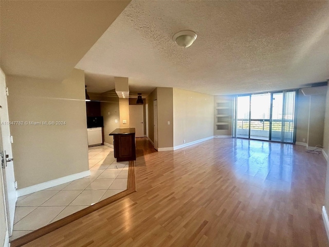 unfurnished living room featuring floor to ceiling windows, a textured ceiling, and light hardwood / wood-style flooring