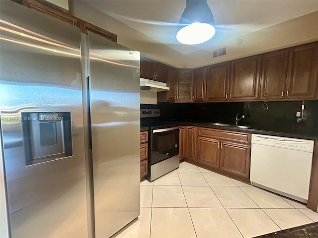 kitchen with appliances with stainless steel finishes, light tile patterned floors, tasteful backsplash, and sink