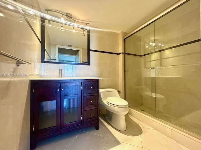 bathroom with vanity, toilet, a shower with shower door, and tile patterned floors