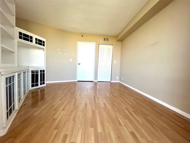 unfurnished living room featuring a textured ceiling and wood-type flooring