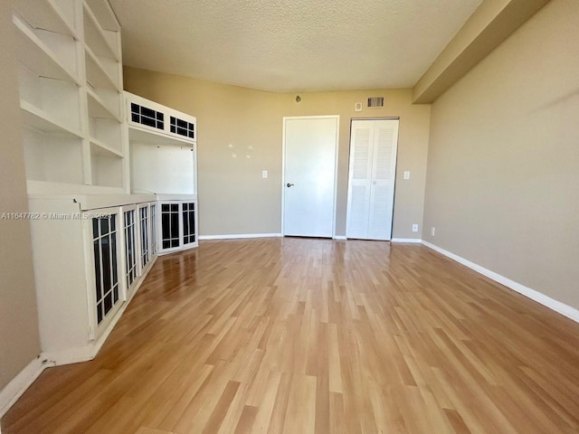 interior space with light wood-type flooring and a textured ceiling