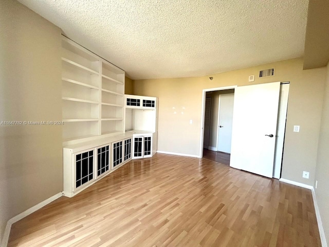 unfurnished living room featuring a textured ceiling and light hardwood / wood-style flooring