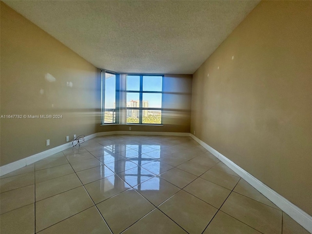 unfurnished room with a textured ceiling and light tile patterned flooring