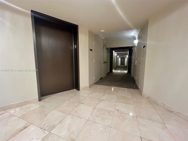 corridor featuring elevator and light tile patterned flooring