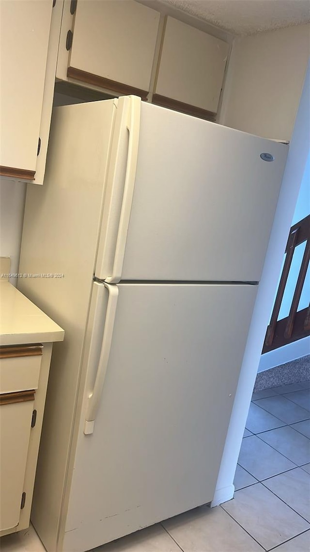 kitchen featuring white fridge, light tile patterned floors, and white cabinets