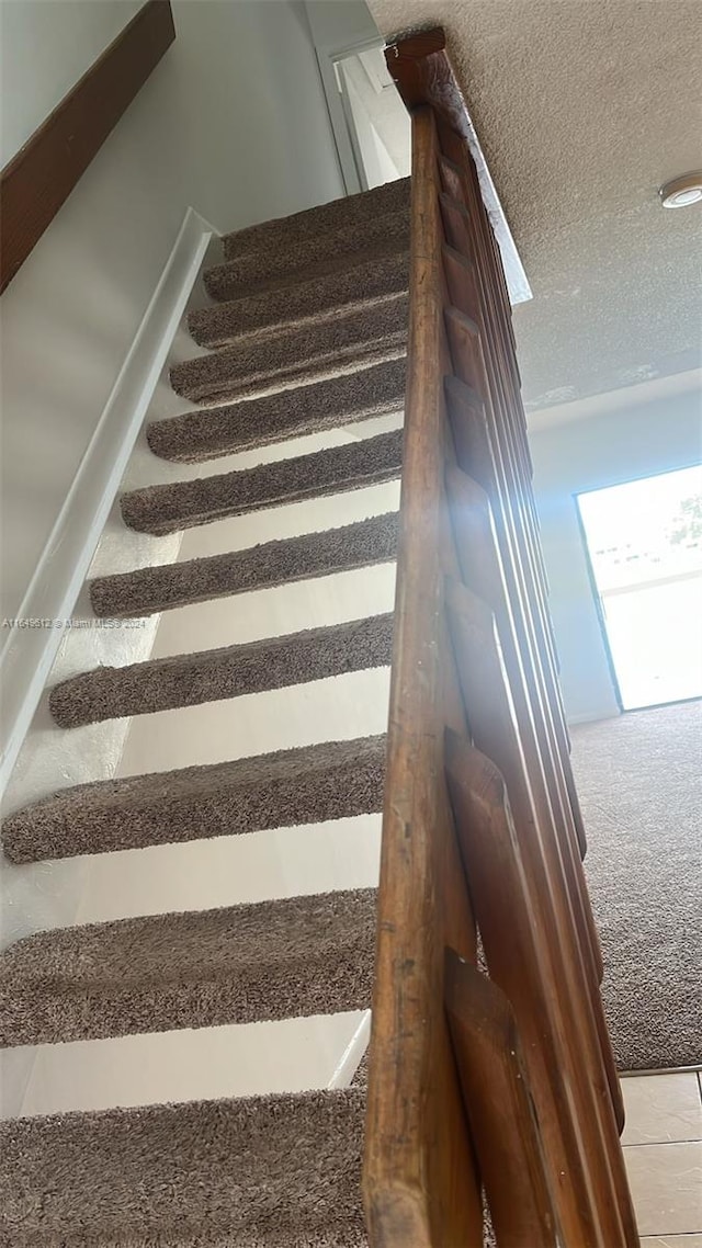 stairs featuring a textured ceiling