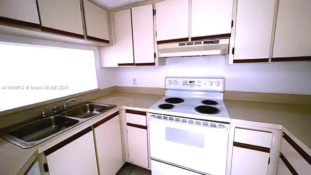 kitchen featuring white range with electric cooktop, sink, and white cabinets