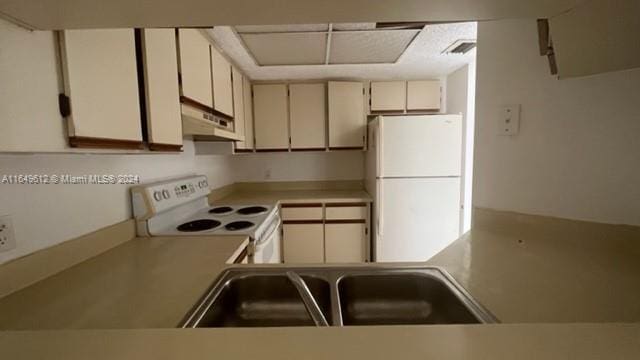 kitchen featuring white appliances, cream cabinets, and sink