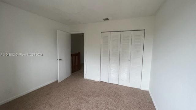 unfurnished bedroom featuring a closet and light carpet