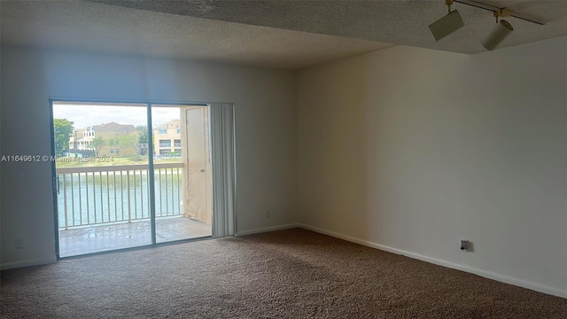 empty room with a textured ceiling, carpet, ceiling fan, and a water view