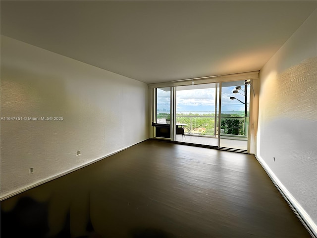 spare room featuring expansive windows and dark wood-type flooring