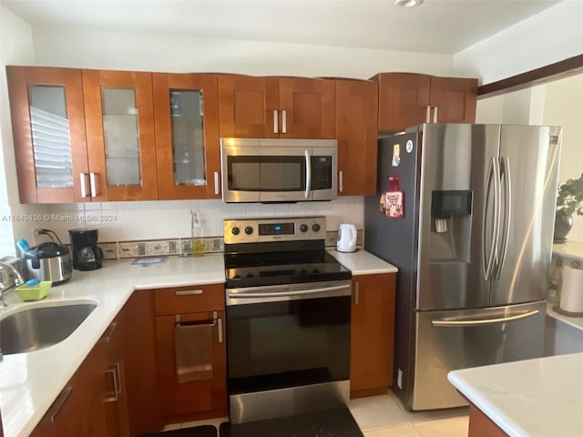 kitchen with light stone counters, light tile patterned flooring, sink, backsplash, and appliances with stainless steel finishes