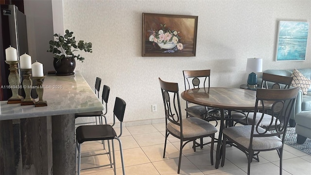 dining area with light tile patterned floors, wallpapered walls, and baseboards