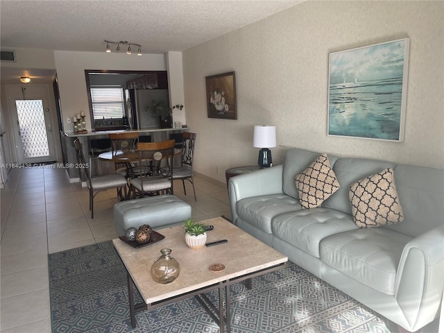 living area featuring track lighting, a textured ceiling, visible vents, and tile patterned flooring