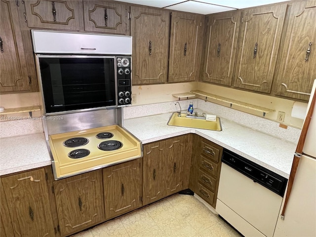 kitchen with white appliances, dark brown cabinets, light countertops, and a sink