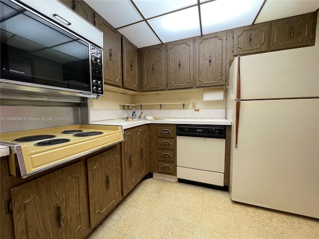 kitchen featuring white appliances, dark brown cabinets, and light tile patterned floors