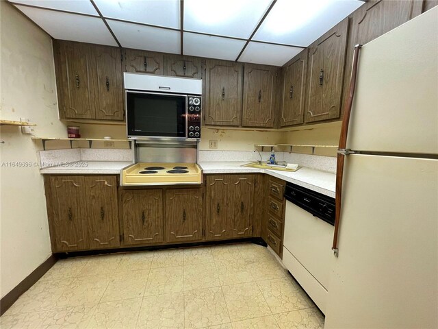 3000 NE 5th Ter Unit 310-A, Wilton Manors, FL 33334 - kitchen featuring white appliances, light countertops, dark brown cabinetry, a paneled ceiling, and light floors