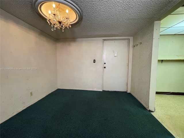 carpeted spare room featuring a textured ceiling and a chandelier