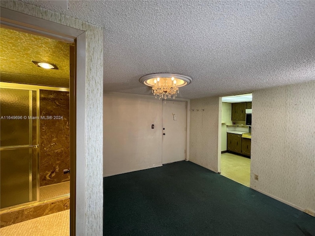 carpeted spare room with an inviting chandelier and a textured ceiling