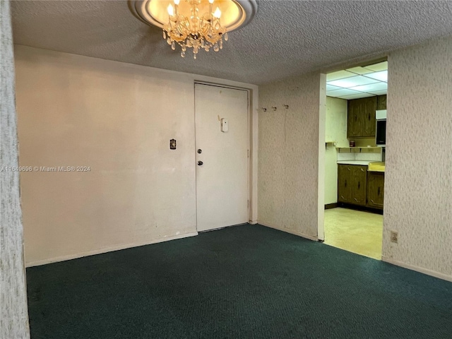 carpeted spare room with a textured ceiling and an inviting chandelier