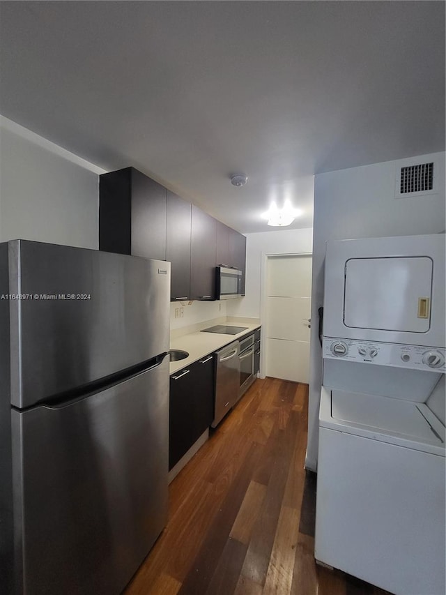 kitchen featuring appliances with stainless steel finishes, sink, stacked washer and dryer, and dark hardwood / wood-style floors