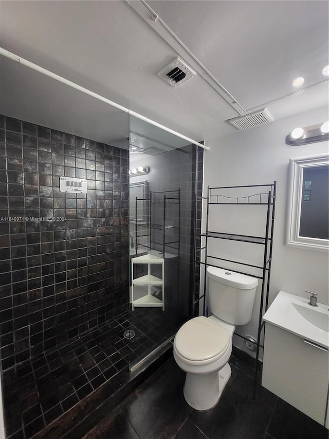 bathroom with vanity, toilet, tile patterned floors, and a tile shower