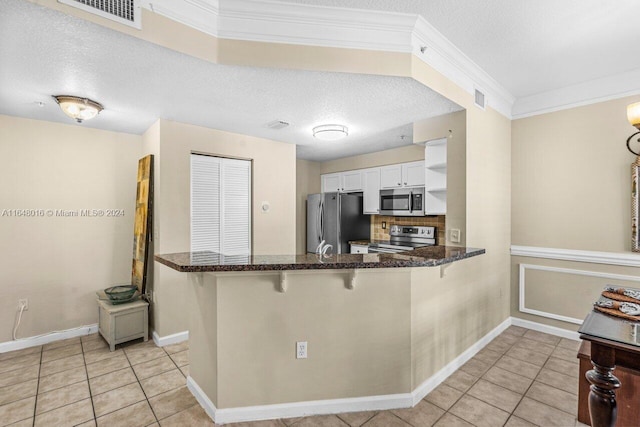 kitchen with backsplash, kitchen peninsula, light tile patterned floors, and appliances with stainless steel finishes