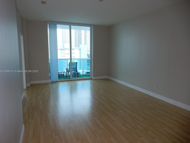 spare room featuring expansive windows and light hardwood / wood-style flooring