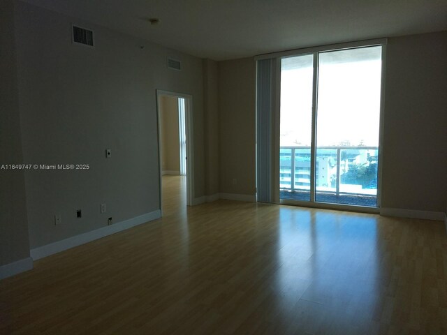 unfurnished room featuring expansive windows and light hardwood / wood-style floors