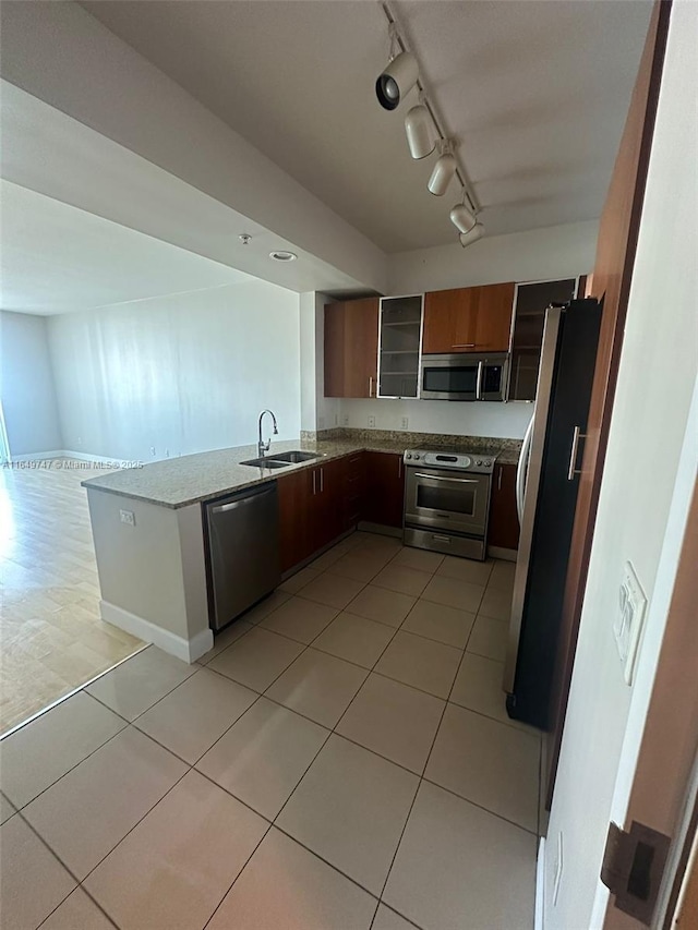 kitchen featuring sink, light tile patterned floors, rail lighting, stainless steel appliances, and kitchen peninsula