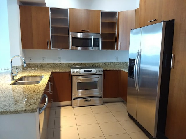 kitchen featuring sink, light stone counters, light tile patterned floors, kitchen peninsula, and stainless steel appliances