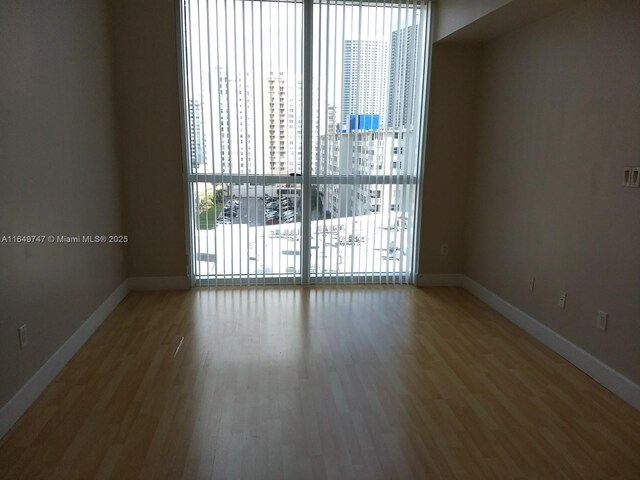 unfurnished room featuring expansive windows, wood-type flooring, and a wealth of natural light