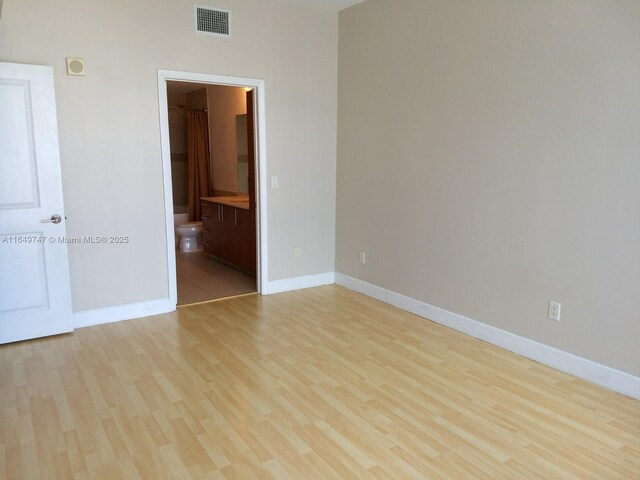 unfurnished bedroom with ensuite bath and light hardwood / wood-style floors