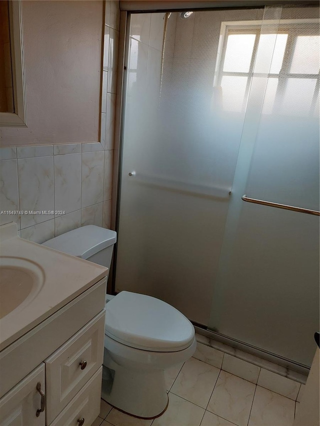 bathroom with vanity, an enclosed shower, tile patterned floors, tile walls, and toilet