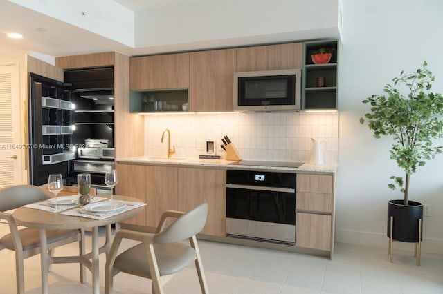 kitchen featuring open shelves, light stone counters, tasteful backsplash, and appliances with stainless steel finishes