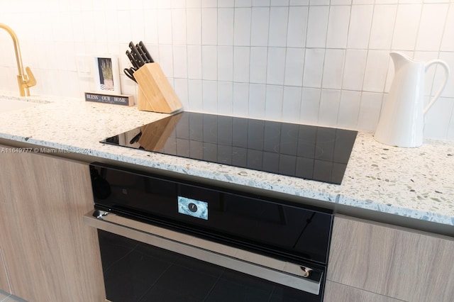 details with oven, modern cabinets, light stone counters, decorative backsplash, and black electric stovetop