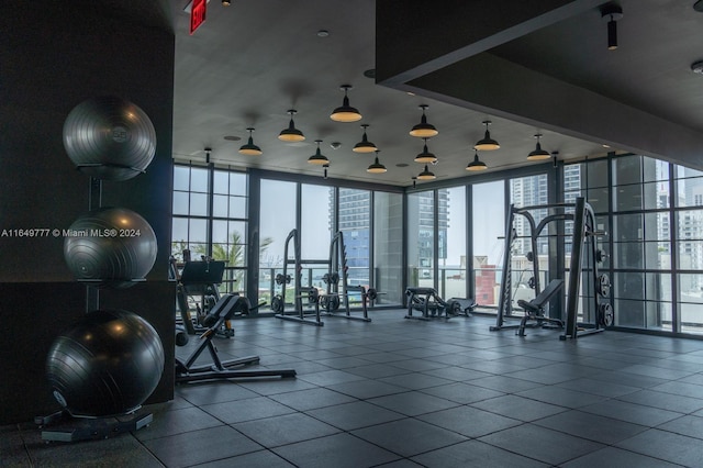 gym featuring dark tile patterned flooring and a wall of windows