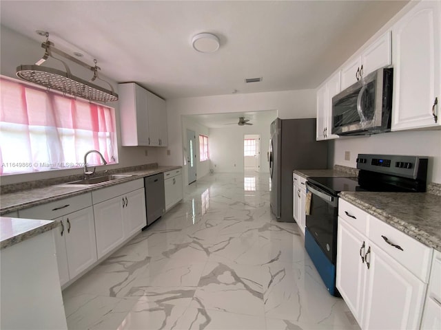 kitchen with light tile patterned floors, stainless steel appliances, sink, white cabinetry, and ceiling fan