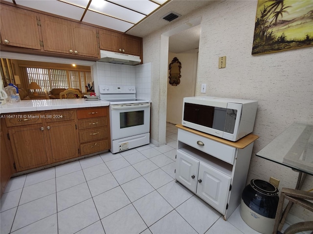 kitchen with white appliances, tile countertops, and light tile patterned floors