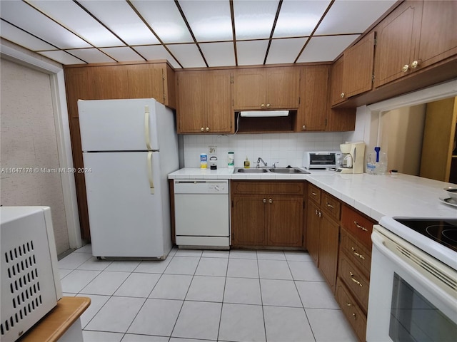 kitchen featuring light tile patterned flooring, tasteful backsplash, white appliances, kitchen peninsula, and sink