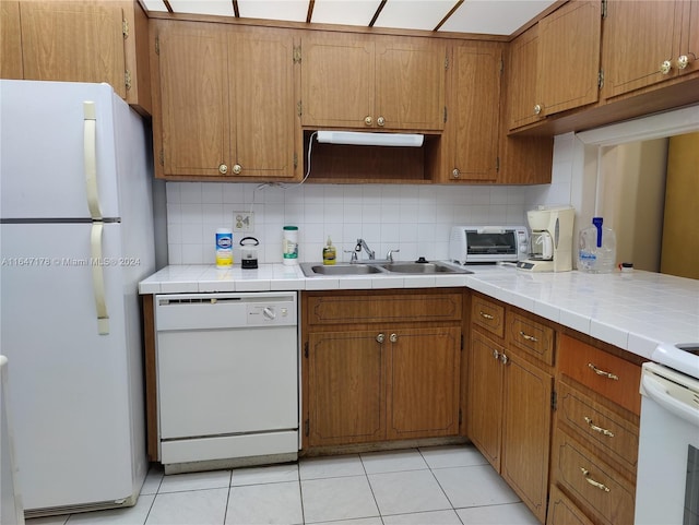 kitchen with tile counters, tasteful backsplash, sink, white appliances, and light tile patterned floors