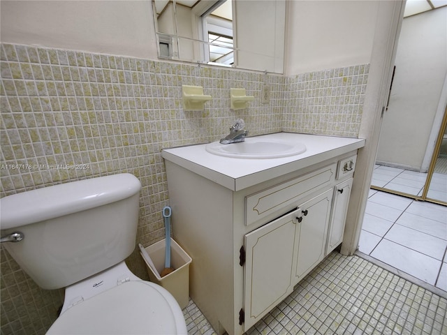 bathroom featuring vanity, tile walls, toilet, and tile patterned floors