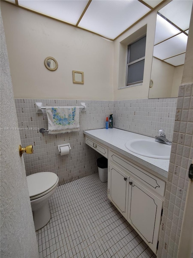 bathroom featuring vanity, tile walls, tile patterned flooring, and toilet