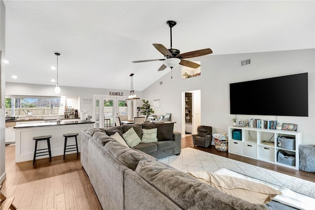 living room featuring light wood-type flooring, ceiling fan, high vaulted ceiling, and french doors