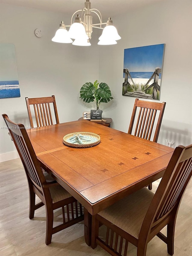 dining area with light hardwood / wood-style flooring and an inviting chandelier