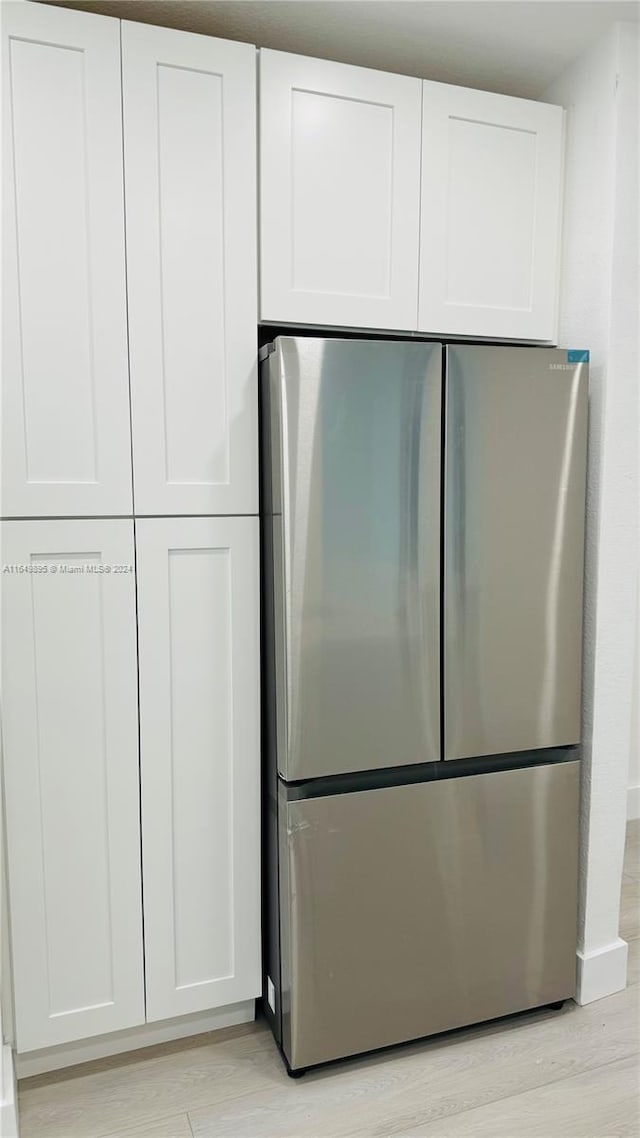 kitchen with stainless steel fridge, light hardwood / wood-style flooring, and white cabinets