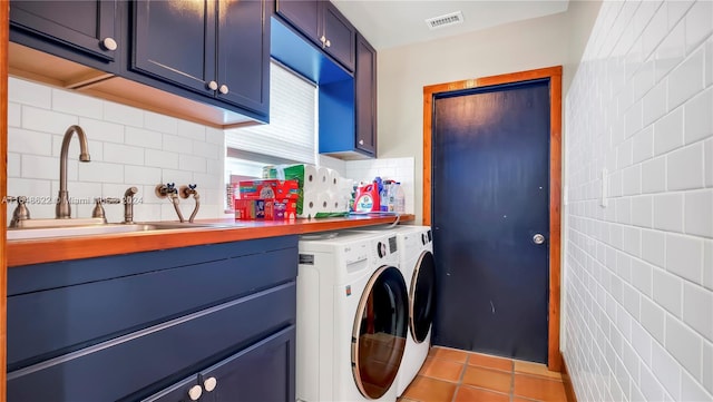 clothes washing area featuring tile patterned flooring, washing machine and dryer, cabinets, and sink