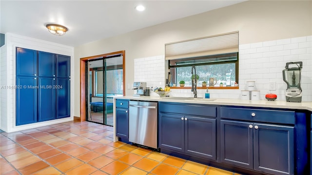 kitchen with blue cabinetry, backsplash, sink, and stainless steel dishwasher